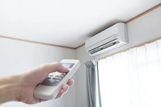 D&L Plumbing Heating Air Conditioning wall unit and hand using remote control